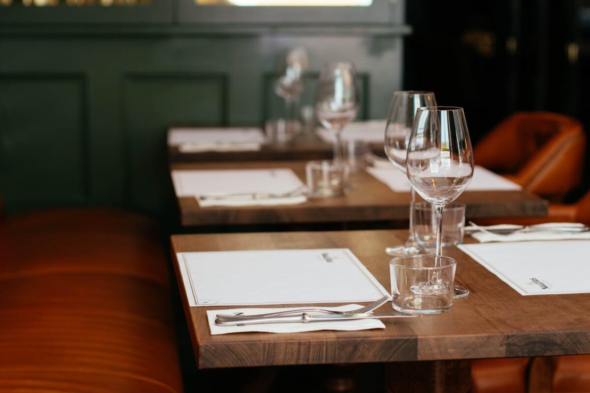 Tables set at a restaurant with placcemats, napkins, cutlery and wine glasses